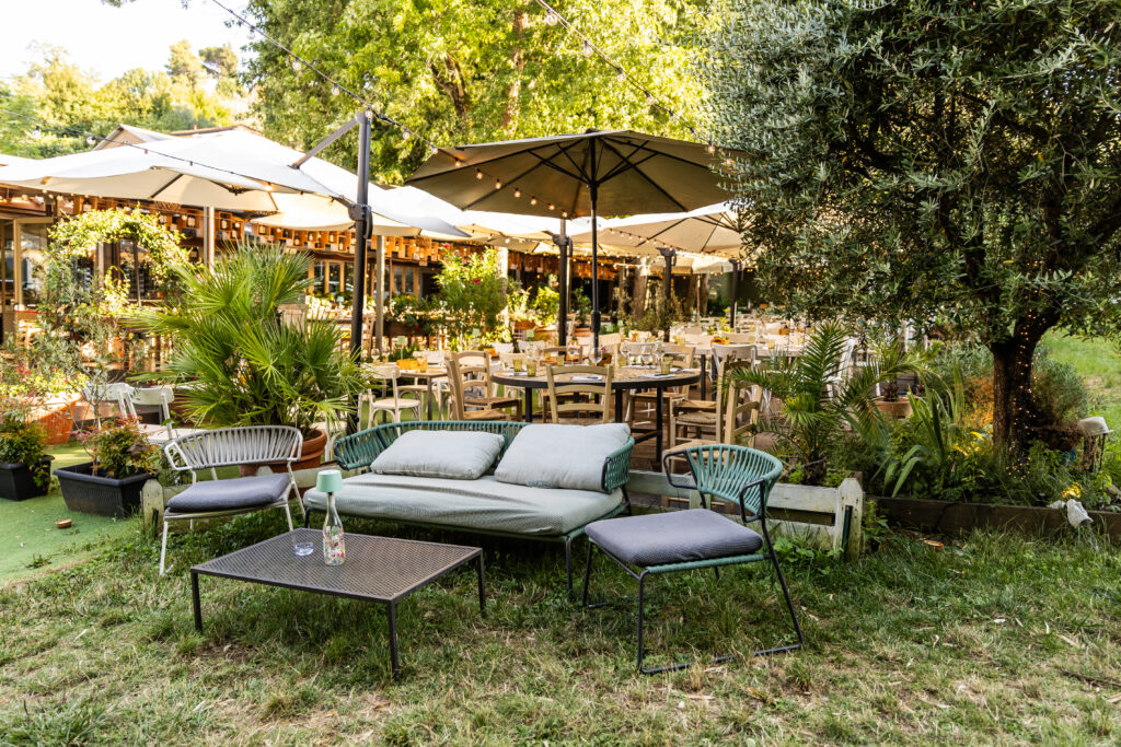 Vista panoramica del dehors con ombrelloni bianchi e tavoli apparecchiati nel giardino